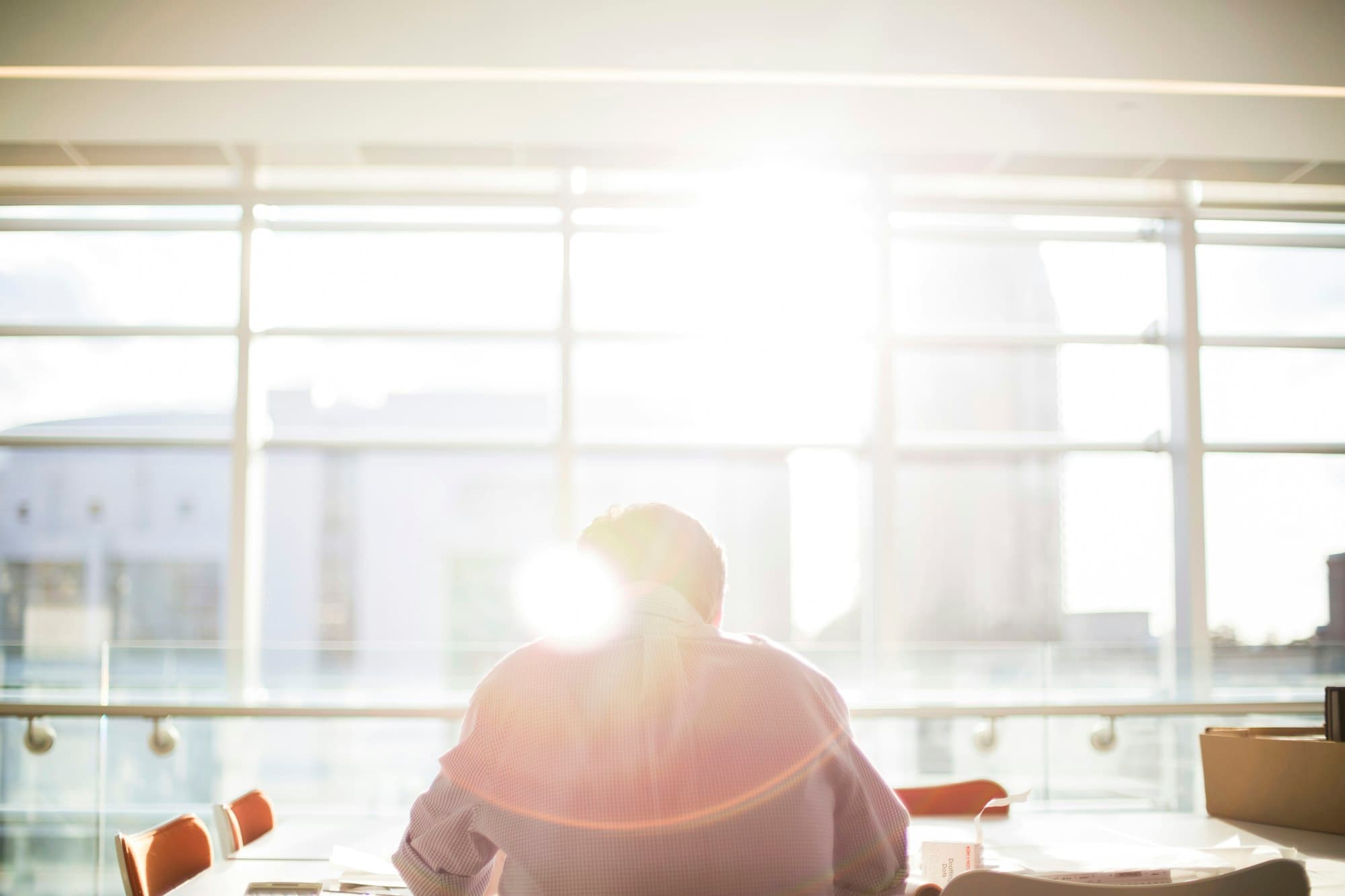 An office worker at a desk against a bright, sunlit window