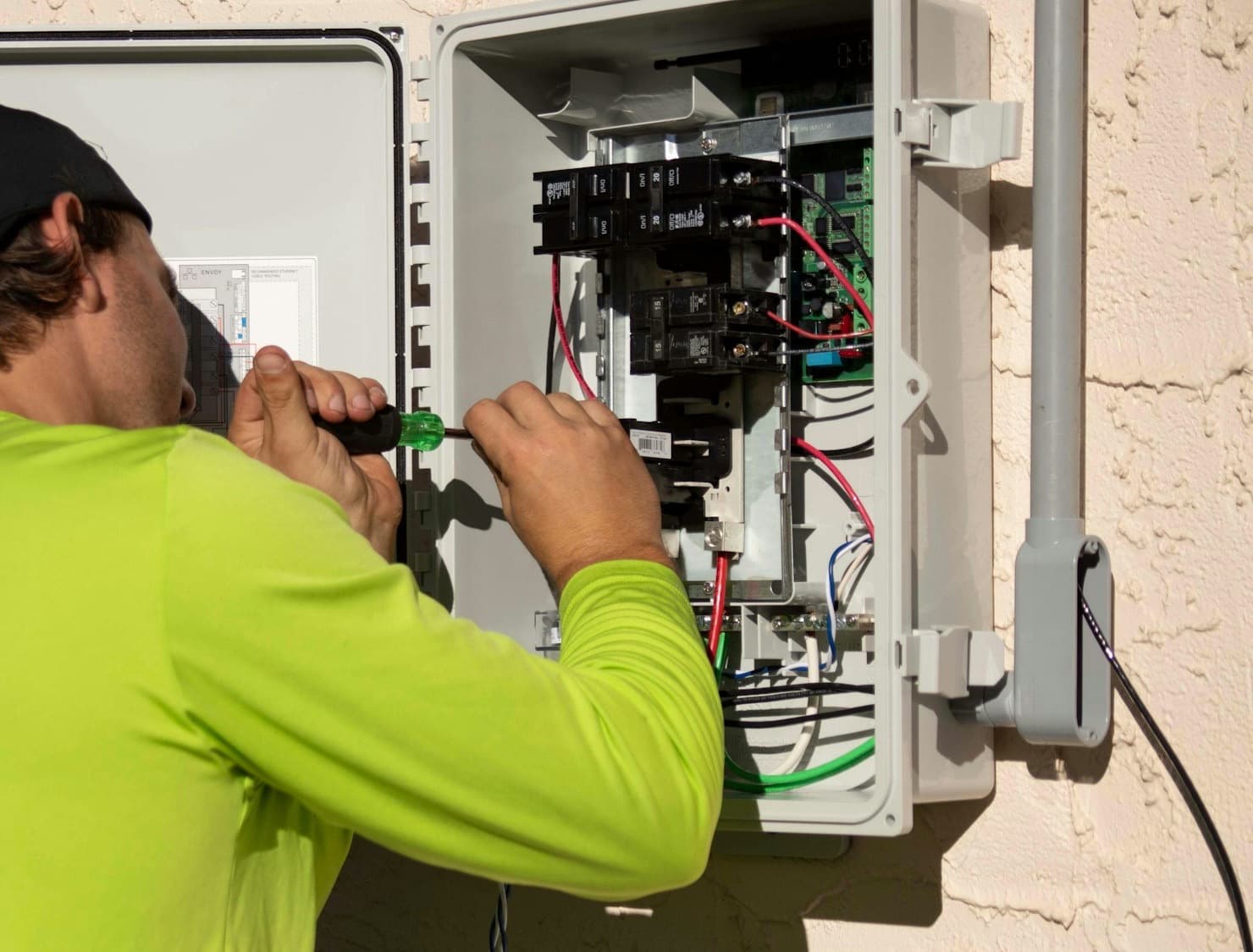 A tradie in a hi-vis shirt working on an electrical panel